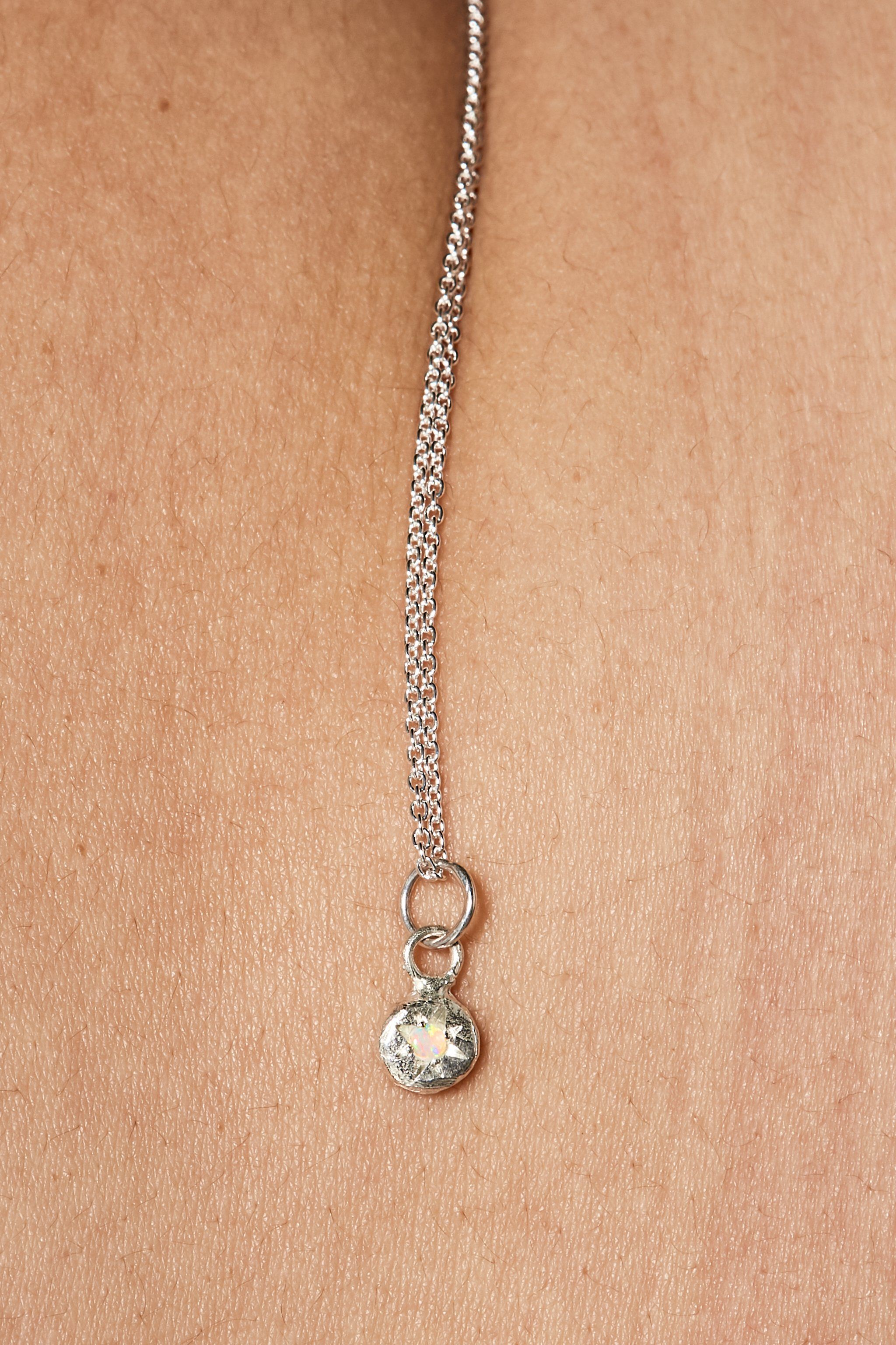 Close-up of opal birthstone charm on silver chain