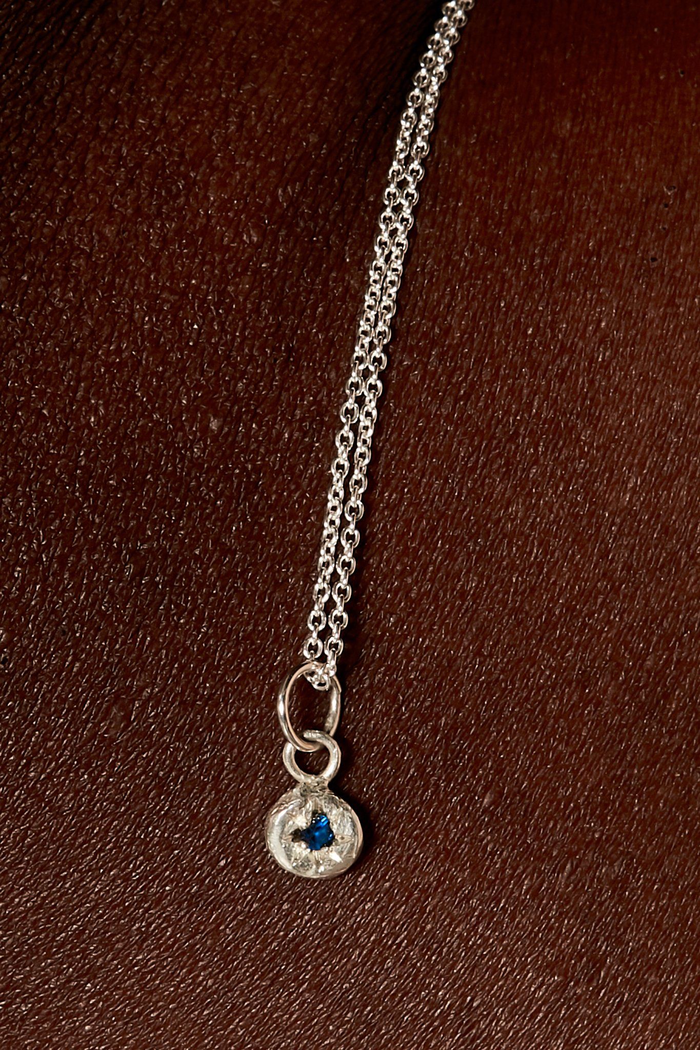 Close-up of dark blue sapphire birthstone charm on silver chain