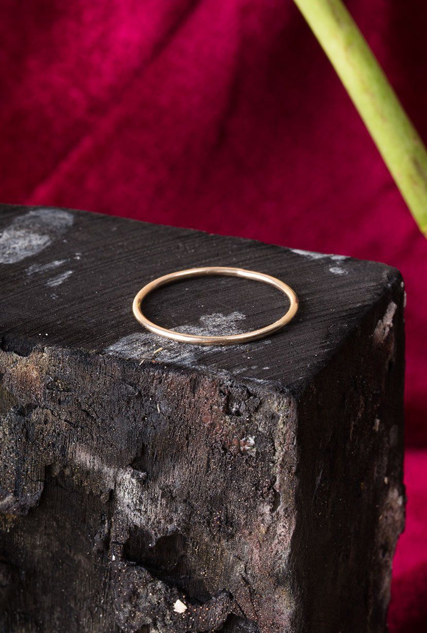 Fine Gold band. round, highly polished, sitting charcoal block.
