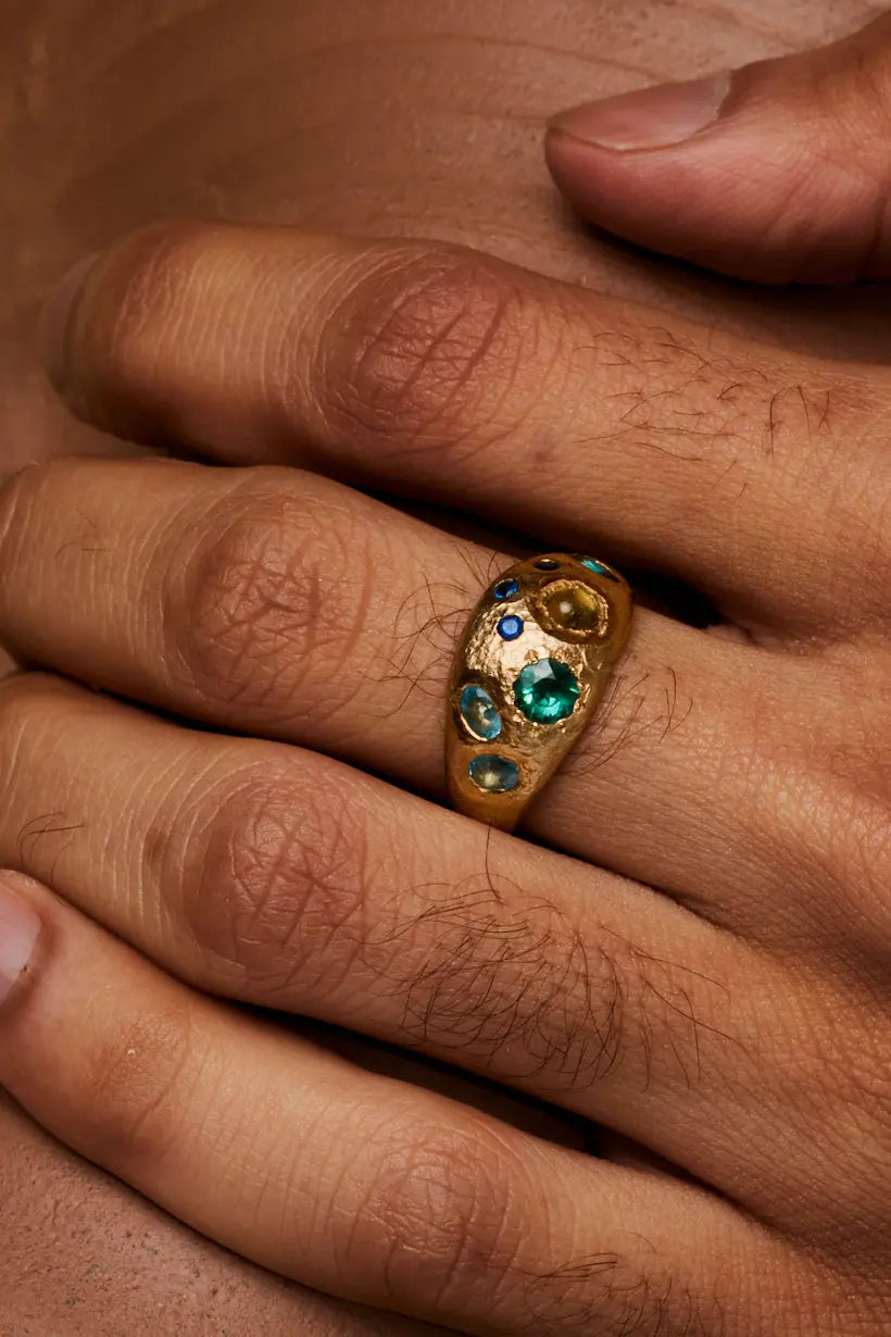 Side view of the Rockpool ring on a models hand. Wide gold wedding band with a sparkling teal tourmaline.