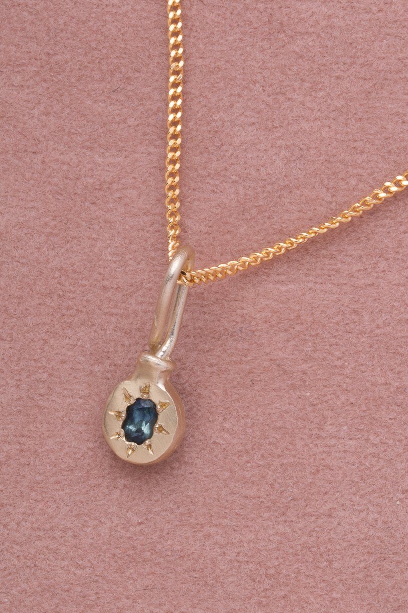 Teal Australian sapphire star set in golden pendant on a gold chain