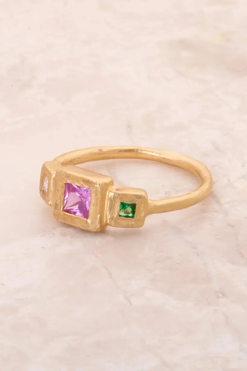 Close-up of hot pink sapphire centre stone in bezel setting, with diamond and tsavorite garnet