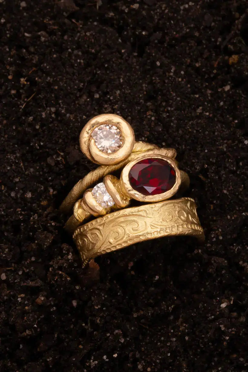 Golden Bramble Ring featuring garnet and diamond photographed in soil with the Poet's Ring and Honeysuckle Ring