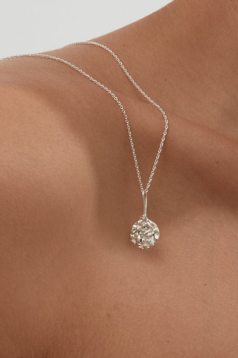 Floral Relic pendant in sterling silver on a delicate sterling silver chain, lying over the model's shoulder